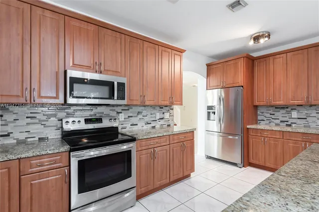 a kitchen with stainless steel appliances granite countertop a stove microwave refrigerator and sink