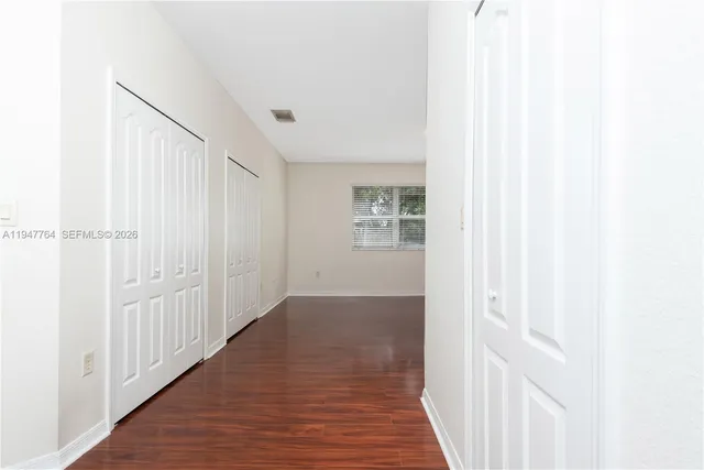 a view of a hallway with wooden floor and entryway