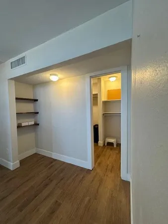 a view of empty room with wooden floor and closet