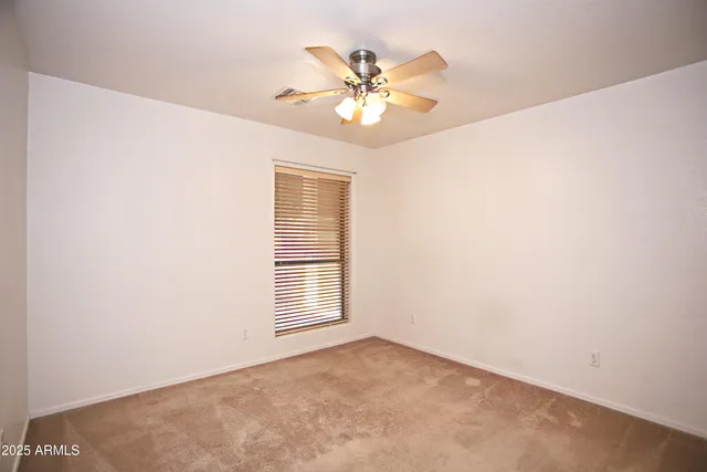 an empty room with window and chandelier fan