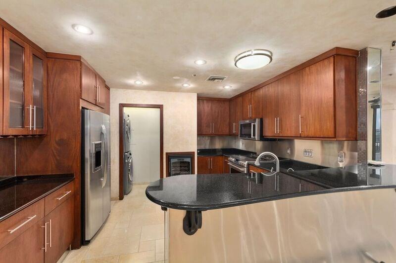40 North Interstate Highway 35, Unit 12C2 Austin, TX 78701 - Photo 16 of 21 Kitchen with a peninsula, glass fronted cabinets, dark stone countertops, stainless steel appliances, and a kitchen bar