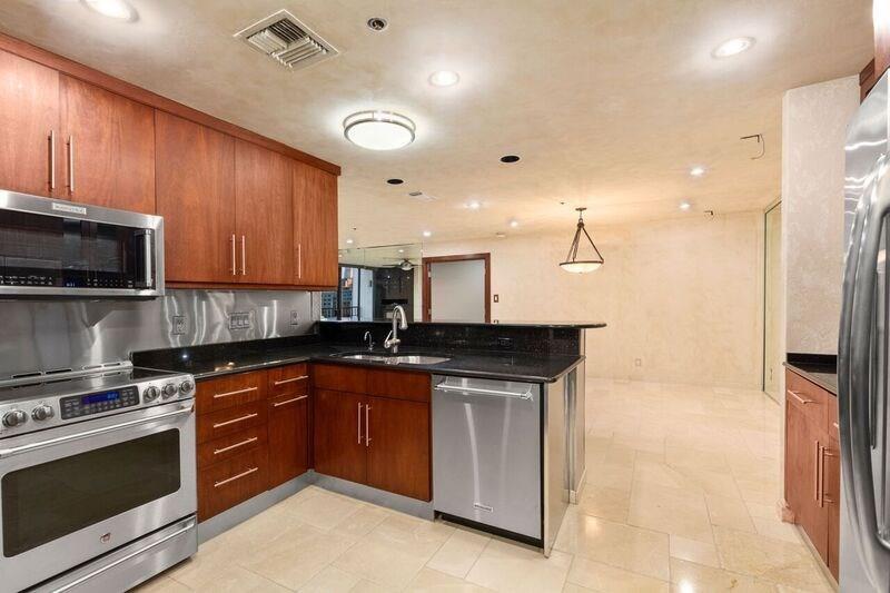 40 North Interstate Highway 35, Unit 12C2 Austin, TX 78701 - Photo 19 of 21 Kitchen with stainless steel appliances, a peninsula, hanging light fixtures, dark stone countertops, and wood finish cabinetry