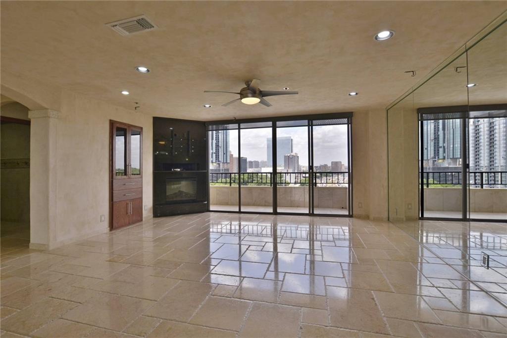 40 North Interstate Highway 35, Unit 12C2 Austin, TX 78701 - Photo 2 of 21 Empty room featuring stone tile flooring, arched walkways, a ceiling fan, a view of city, and expansive windows