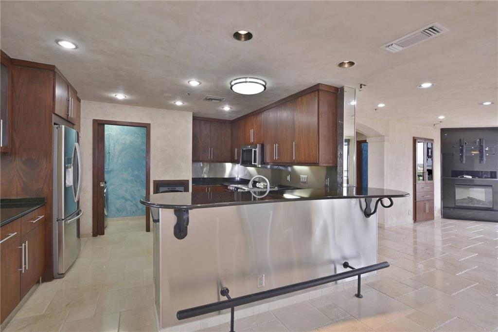 40 North Interstate Highway 35, Unit 12C2 Austin, TX 78701 - Photo 4 of 21 Kitchen featuring a peninsula, a breakfast bar area, stainless steel appliances, dark stone countertops, and arched walkways