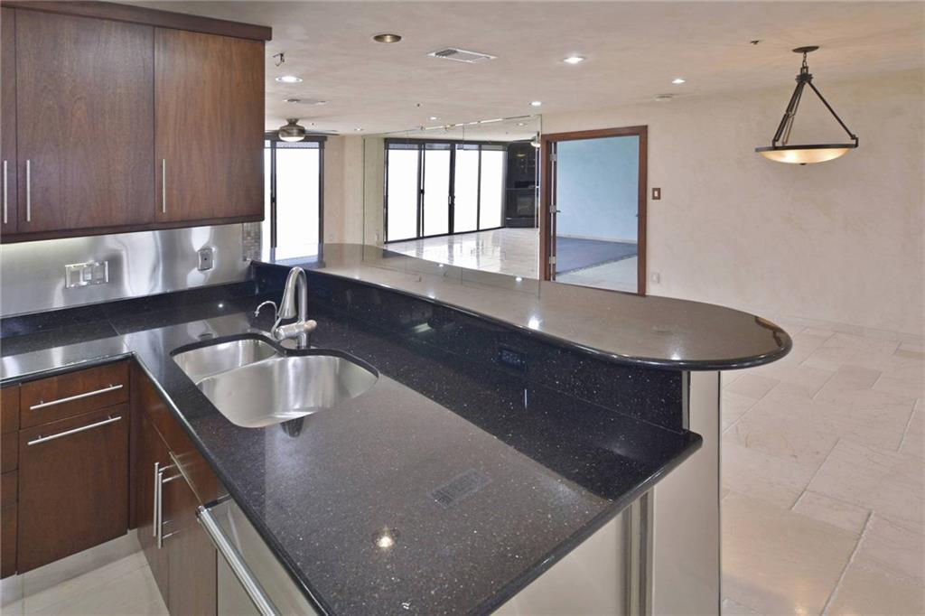 40 North Interstate Highway 35, Unit 12C2 Austin, TX 78701 - Photo 21 of 21 Kitchen with a peninsula, dark stone countertops, open floor plan, and dark wood finish cabinets