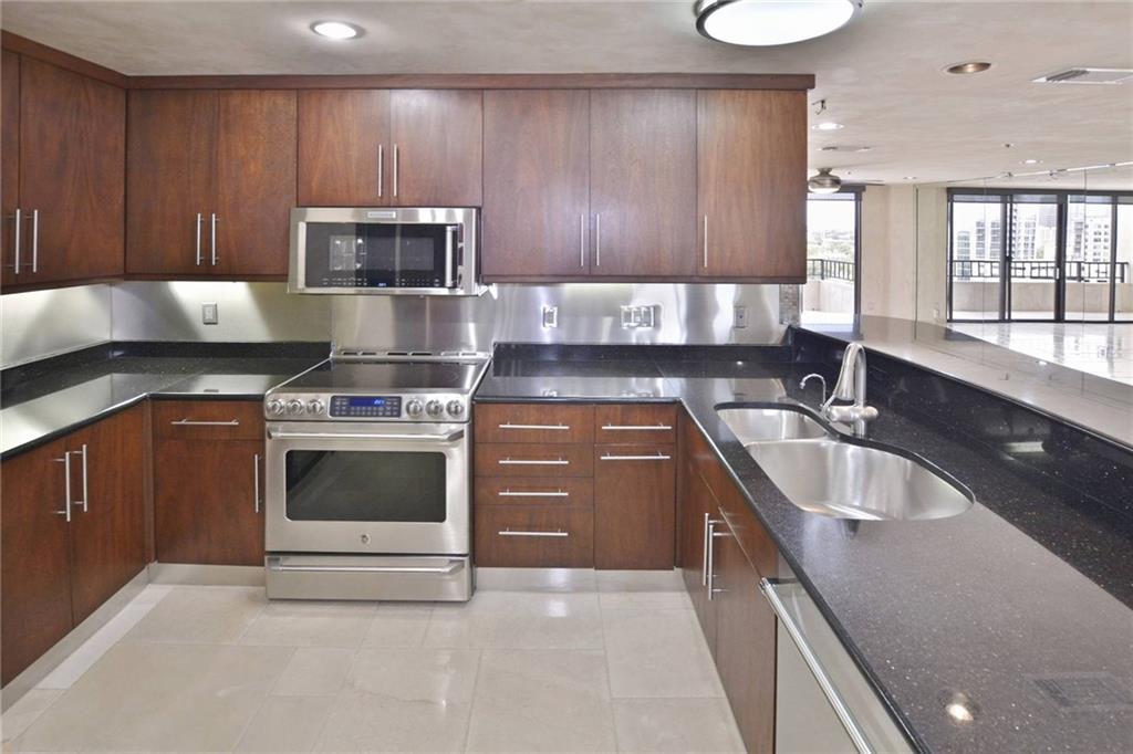40 North Interstate Highway 35, Unit 12C2 Austin, TX 78701 - Photo 5 of 21 Kitchen featuring stainless steel appliances, dark stone countertops, and light tile patterned floors