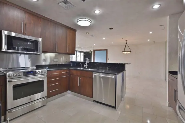 a kitchen with stainless steel appliances granite countertop a sink a refrigerator and wooden cabinets