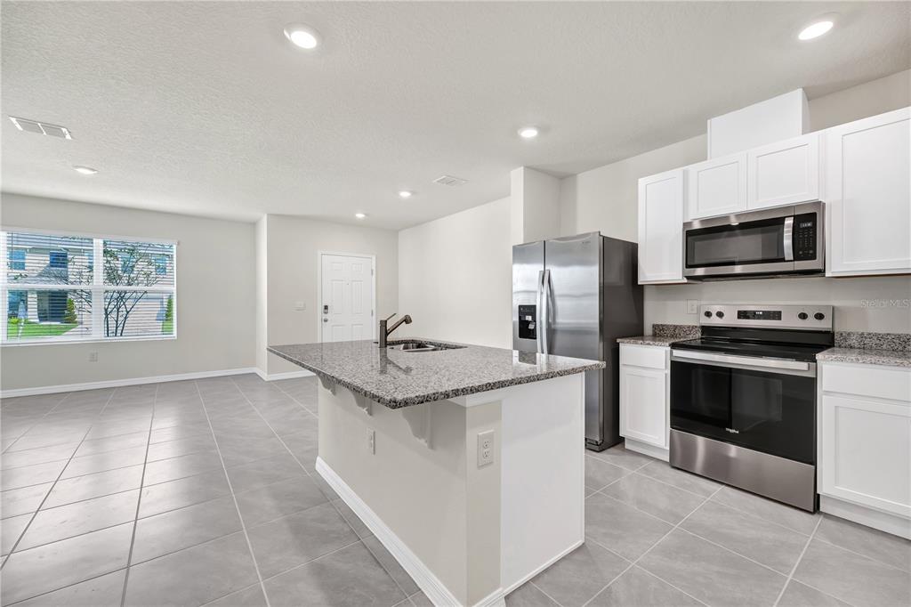 5650 Anders Way St. Cloud, FL 34771 - Photo 11 of 39 a kitchen with stainless steel appliances granite countertop a sink stove and refrigerator