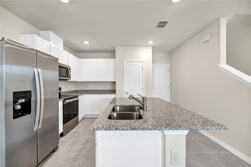 5650 Anders Way St. Cloud, FL 34771 - Photo 14 of 39 a kitchen with granite countertop a sink and refrigerator