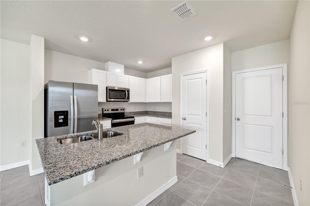 5650 Anders Way St. Cloud, FL 34771 - Photo 15 of 39 a kitchen with stainless steel appliances granite countertop a sink stove and refrigerator