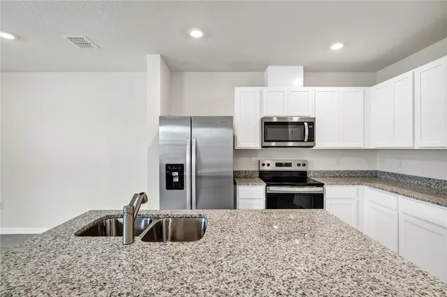 a kitchen with granite countertop a sink and stainless steel appliances