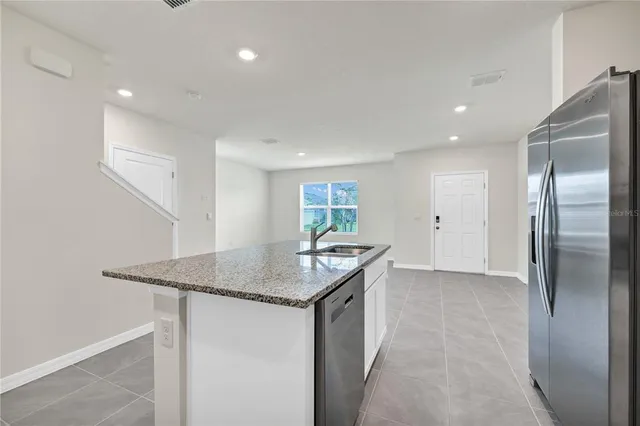 a kitchen with stainless steel appliances granite countertop a sink a refrigerator and a granite counter tops