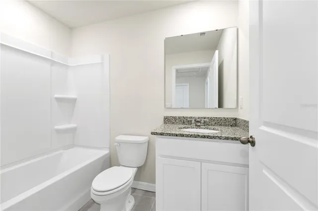 a bathroom with a granite countertop toilet a sink and a bathtub