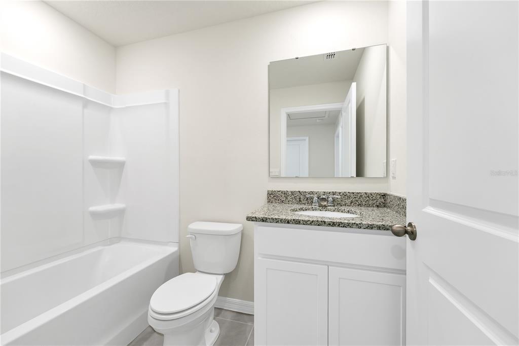 5650 Anders Way St. Cloud, FL 34771 - Photo 5 of 39 a bathroom with a granite countertop toilet a sink and a bathtub