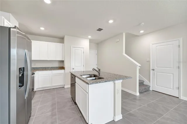 a kitchen that has a lot of white cabinets and stainless steel appliances