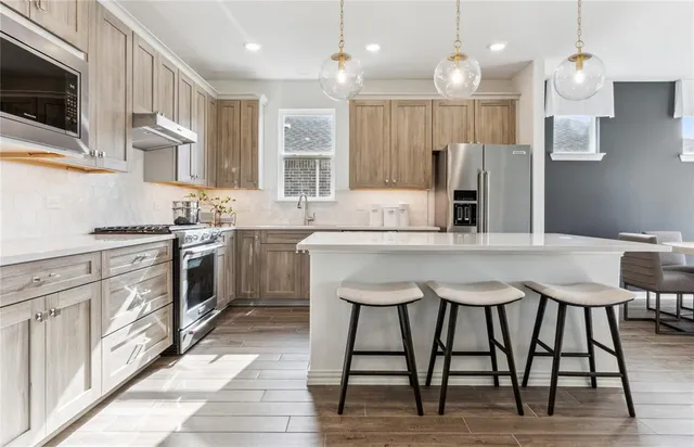 a kitchen with stainless steel appliances kitchen island granite countertop a sink a stove a dining table and chairs