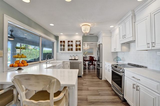a large kitchen with stainless steel appliances granite countertop a stove and a view of living room