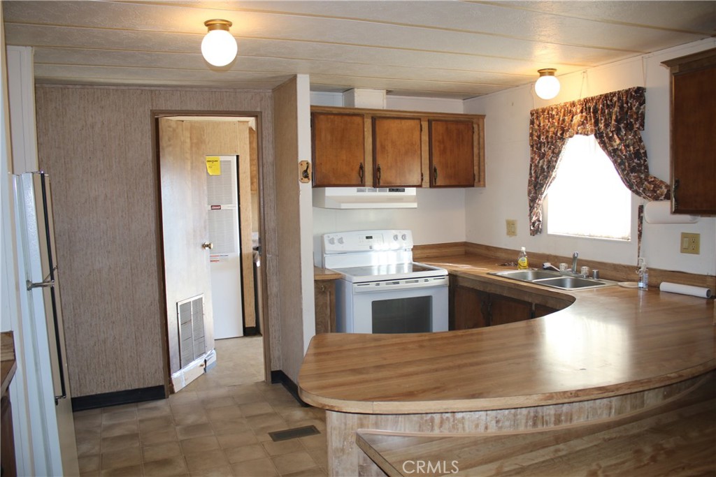 1147 Cherokee Trail Yucca Valley, CA 92284 - Photo 6 of 27 a kitchen with stainless steel appliances granite countertop a sink and a refrigerator
