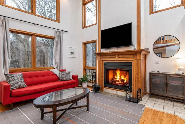 a view of a livingroom with furniture a fireplace wooden floor and windows