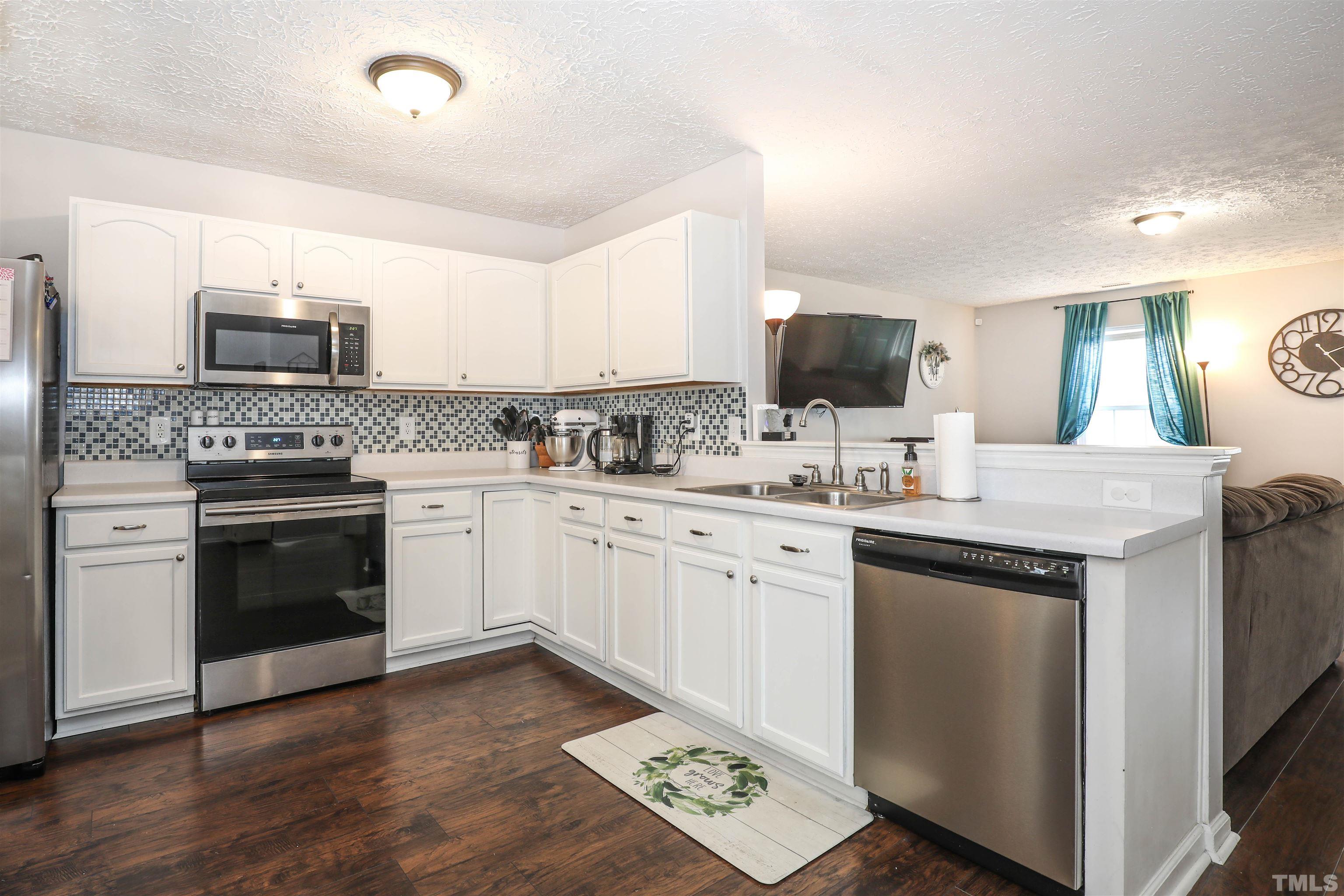 5805 Wynmore Road Raleigh, NC 27610 - Photo 10 of 20 a kitchen with stainless steel appliances white cabinets a sink and a stove