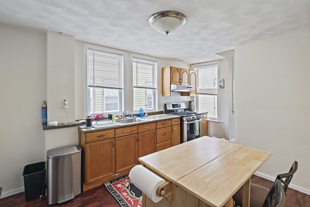 105 Walnut Street Somerville, MA 02145 - Photo 17 of 37 a kitchen with a sink a stove a refrigerator dining table and chairs