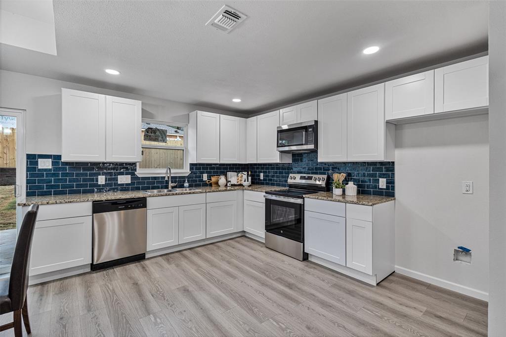 1009 North Barrett Avenue Denison, TX 75020 - Photo 13 of 38 a kitchen with granite countertop white cabinets and white appliances