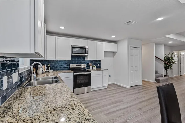 a kitchen with granite countertop a refrigerator and a stove top oven
