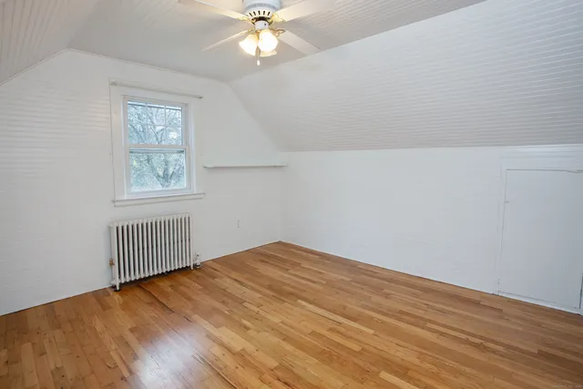 an empty room with wooden floor chandelier fan and windows