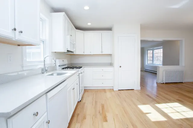 a kitchen with cabinets appliances and a wooden floor