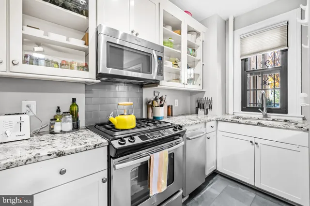 a kitchen with stainless steel appliances granite countertop a stove a sink and a granite counter tops with white cabinets