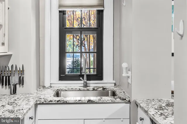 a bathroom with a granite countertop sink and a window