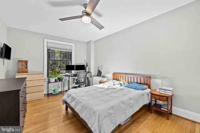 a bedroom with a bed a desk and chair with wooden floor