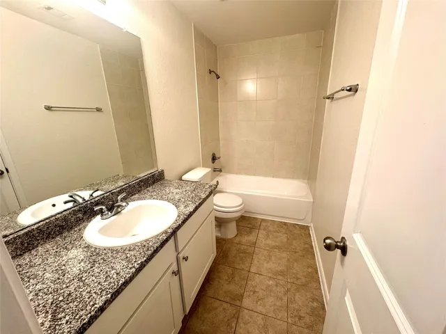 a bathroom with a granite countertop sink a mirror a bathtub and shower