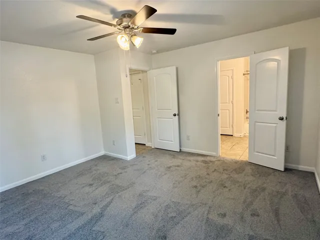 an empty room with closet and a ceiling fan