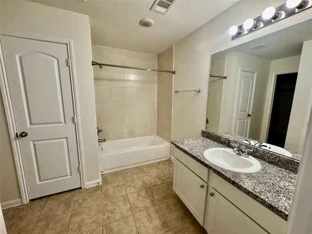 a bathroom with a granite countertop sink a mirror and a bathtub