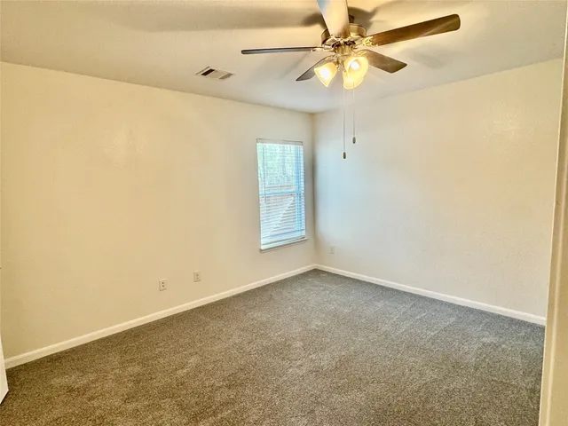 an empty room with a window and a fan