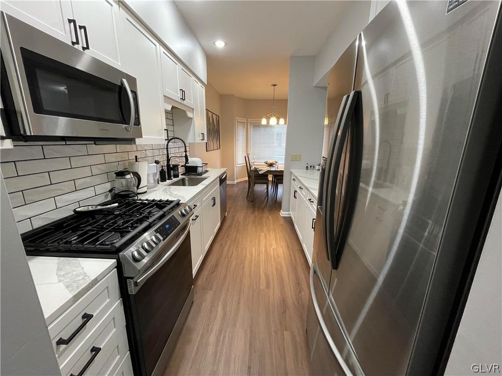 1668 Harding Circle Whitehall, PA 18052 - Photo 7 of 32 a kitchen with stainless steel appliances a stove a microwave a refrigerator a sink and dishwasher with wooden floor