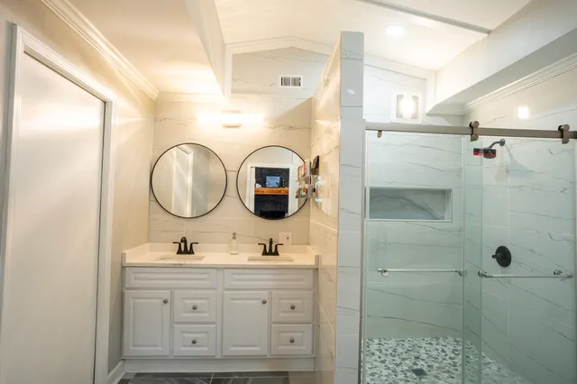 a bathroom with a double vanity sink mirror and shower