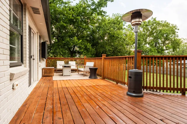 a view of a roof deck with table and chairs a barbeque with wooden floor
