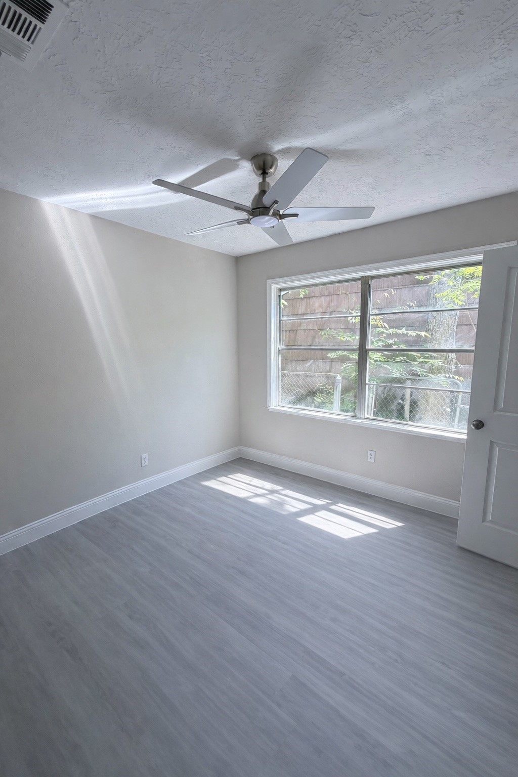 8115 Redfern Drive Houston, TX 77033 - Photo 6 of 7 an empty room with wooden floor chandelier fan and windows
