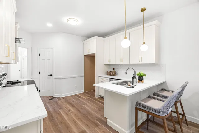 a white kitchen with a table chairs refrigerator and a sink