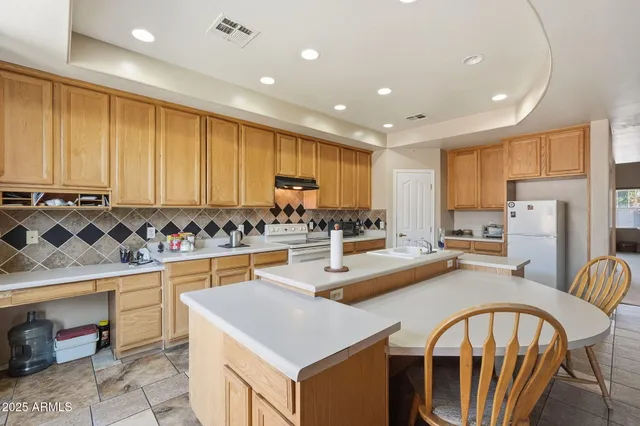 a kitchen with stainless steel appliances granite countertop a stove a sink a refrigerator a center island and chairs