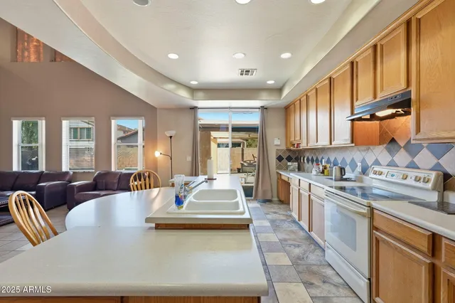 a large kitchen with stainless steel appliances granite countertop a lot of counter space cabinets and a couch