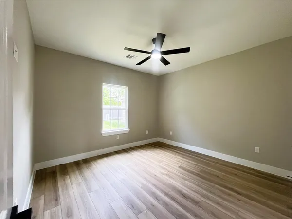 an empty room with wooden floor and windows