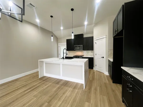 a view of a kitchen with kitchen island microwave and stove top oven