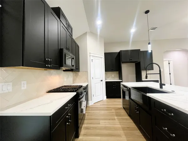a kitchen with stainless steel appliances granite countertop a sink a stove and a refrigerator
