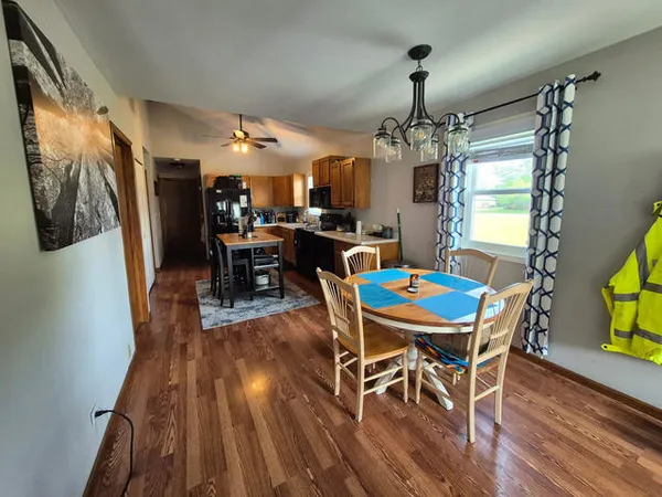 a dining room with wooden floor a chandelier a wooden table and chairs