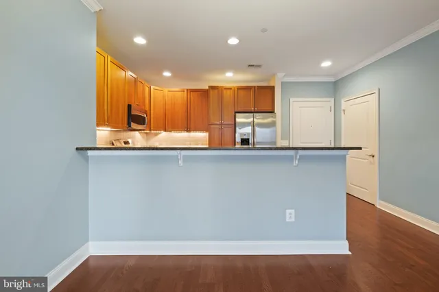 a view of kitchen with kitchen island a sink wooden floor and a refrigerator