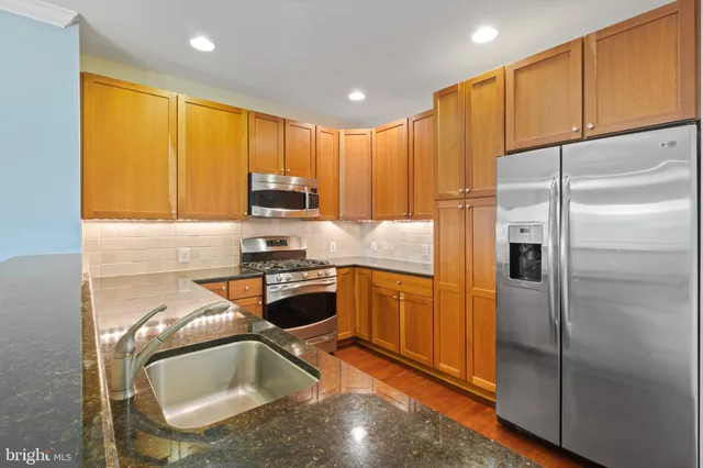 a kitchen with stainless steel appliances granite countertop a refrigerator a sink a stove and a microwave