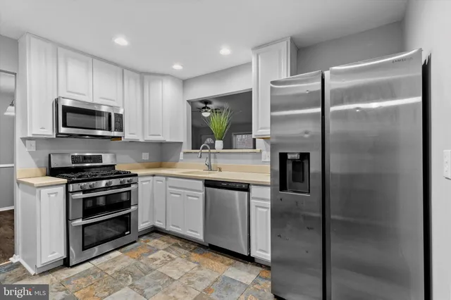 a kitchen with stainless steel appliances granite countertop a refrigerator a stove a sink and a microwave